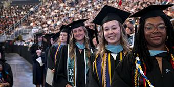 graduating students line up to receive their diplomas during commencement ceremony.