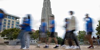 students walking past Cathedral of Learning to get to Honors Orientation; movement captured in their blurred figures.